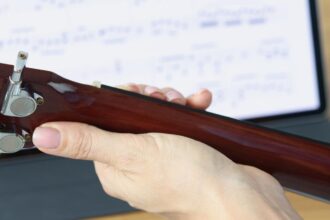 Gitara w kobiecych rękach na tle tabletu z zbliżeniem nut