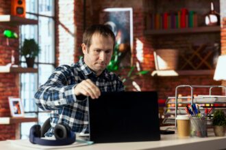 Worker at home office desk opening laptop starting work