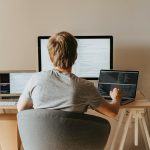 Teen programming with multiple laptops in a modern workspace. Ideal for tech and education themes.